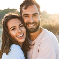 Smiling couple with beautiful, healthy teeth standing outside