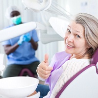 Older woman in dental chair giving thumbs up