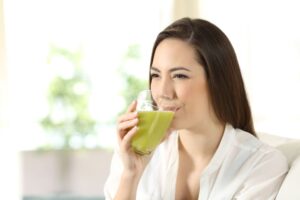 Woman sitting on couch, sipping a green smoothie