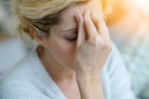 Woman touching her forehead, suffering from a migraine