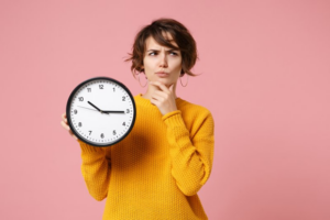 Woman holding a clock and wondering about holiday oral surgery recovery