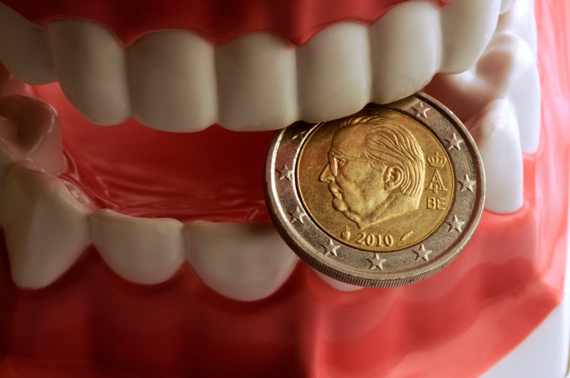 Model of teeth with gum disease holding a coin